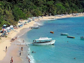 A beach with a boat named 'Glass Bottom Boat' anchored near the shore, surrounded by beachgoers and umbrellas. - Private Pool & Jacuzzi Villa in Sosúa (Sosúa)