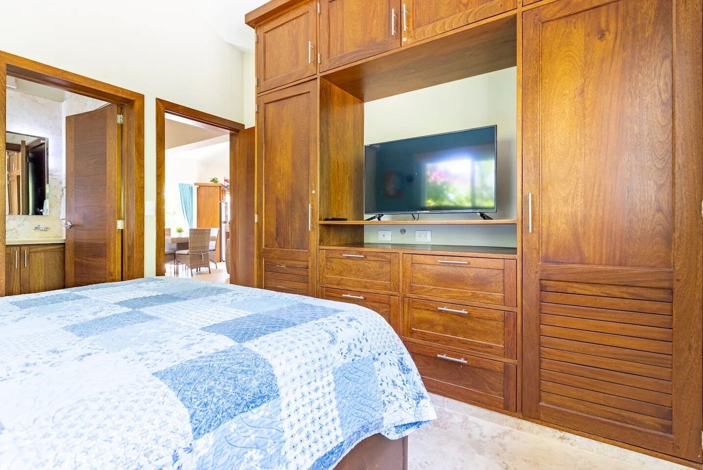 A bedroom with a large bed, wooden wardrobe, and a television.