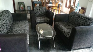 A living room with leopard print sofas, a glass coffee table, and a dining area with wooden chairs and a table. - Tiny Holiday Resort (Dambulla)