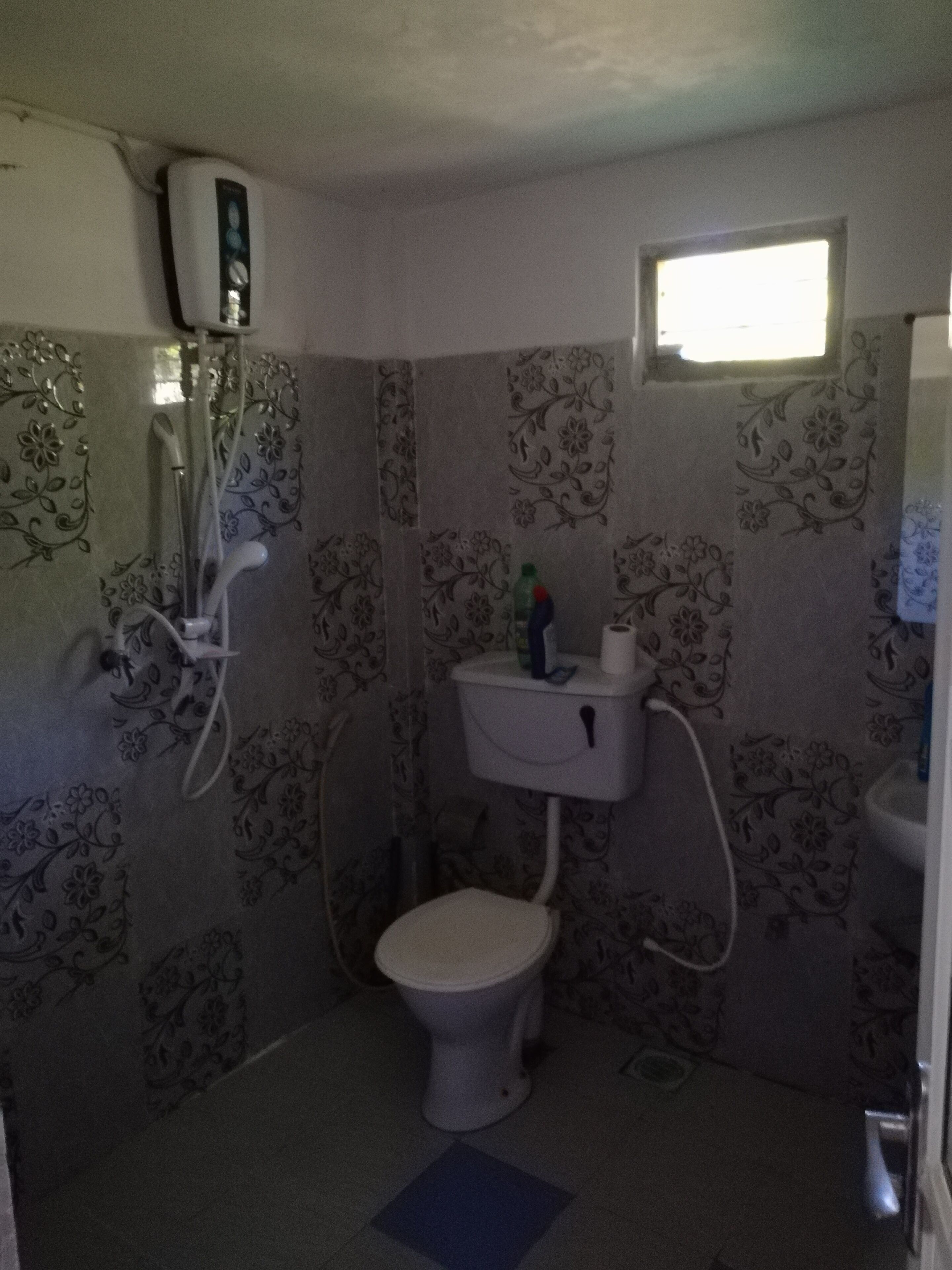 Un baño pequeño con inodoro, ducha y ventana.