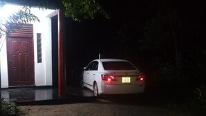 A white car parked in front of a building with a red door and a small window. - Tiny Holiday Resort (Dambulla)