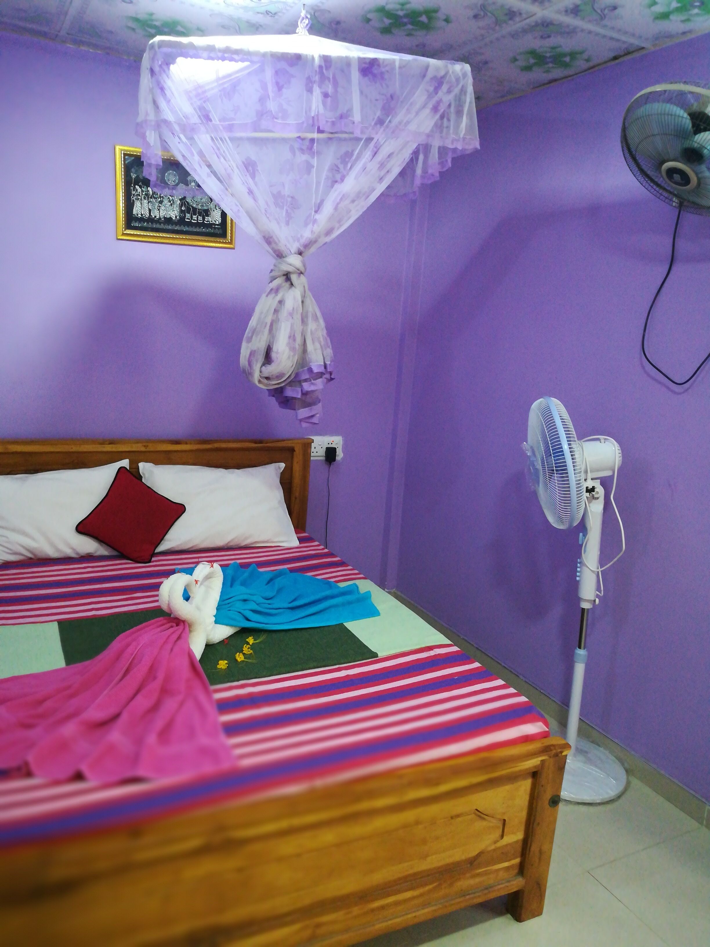 Quarto com cama, ventilador e mosquiteiro.