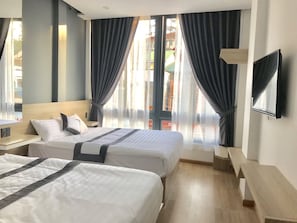 A hotel room with two beds, a TV, and a window with curtains. - Ha Anh Hotel (Xuan Huong - Da Lat)