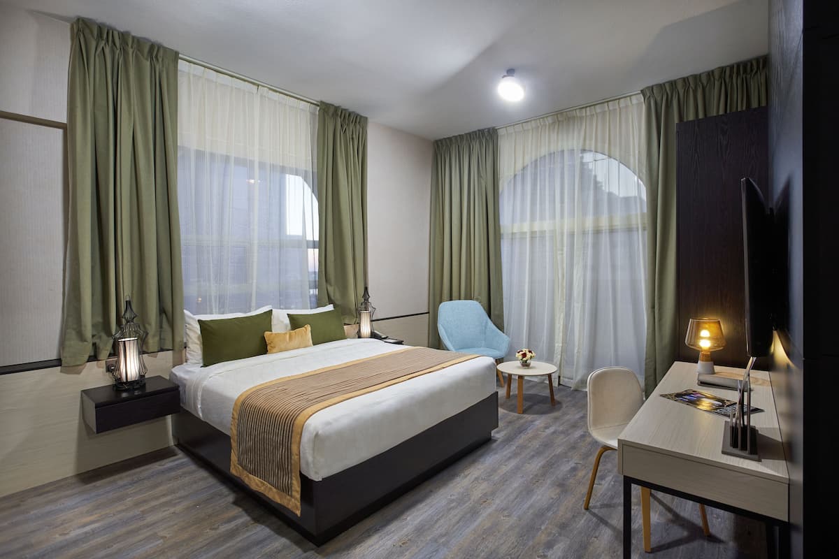 Une chambre d’hôtel avec un lit, un bureau, une chaise et une table de chevet.