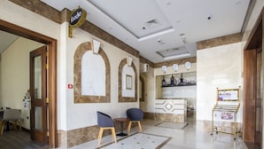 A lobby with a reception desk, two chairs, a small table, and a bulletin board. - Express By TIME - Al Khan (Sharjah)