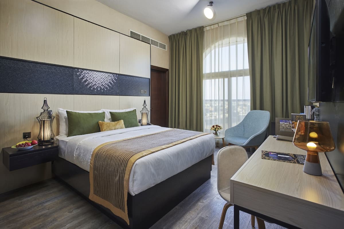 Une chambre d’hôtel avec un grand lit, des tables de chevet, un bureau et une chaise.