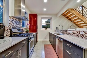 Eine moderne Küche mit Gasherd, Backofen und einer roten Akzentwand.