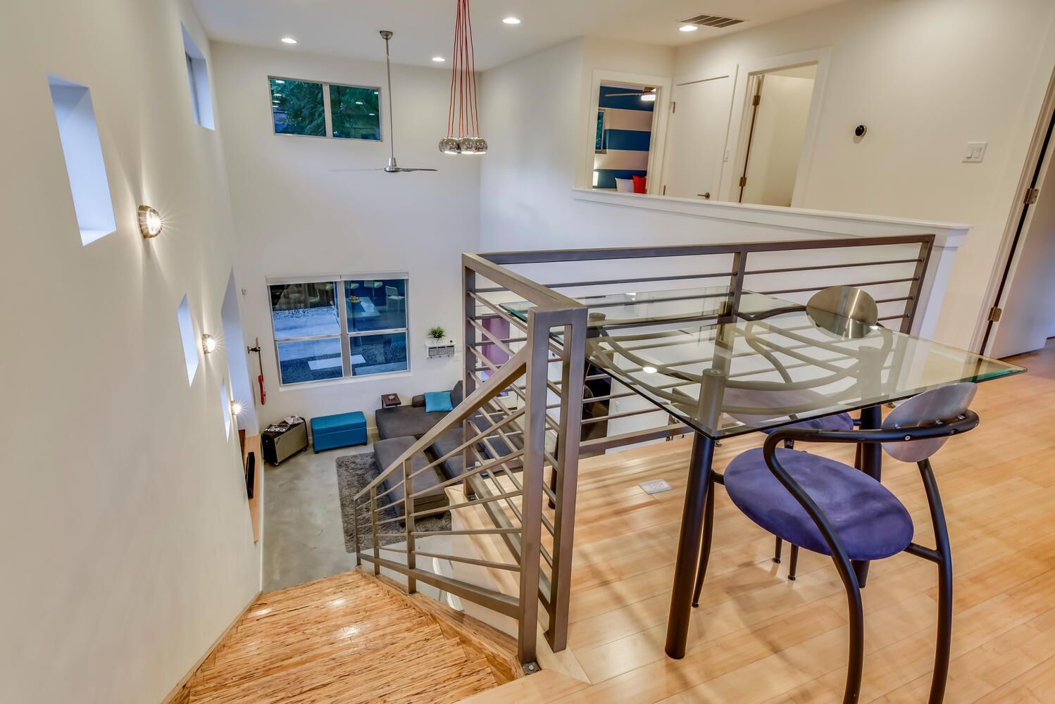Un intérieur moderne avec une table en verre, des rampes en métal et un escalier.