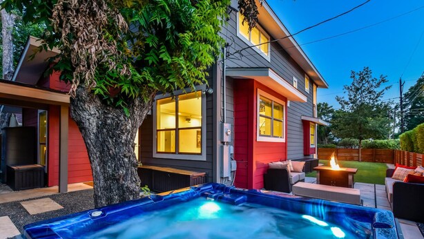 A modern house with a hot tub, outdoor seating, and a tree. - Downtown Austin Luxury House with Hot Tub + Golf Green + Fire Pit +Patio Misters (Austin)