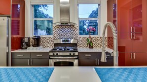 A modern kitchen with a gas stove, oven, and stainless steel cabinets. There are two windows providing natural light and a view of the outside. - Downtown Austin Luxury House with Hot Tub + Golf Green + Fire Pit +Patio Misters (Austin)