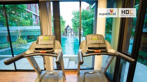 Dos cintas de correr mirando hacia una piscina con vista a un edificio y follaje verde.