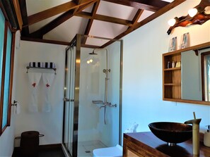 A bathroom with a glass shower enclosure, a wooden vanity with a black bowl sink, and a mirror above the sink. - Dipudo Private Island Resort (Ilagan)