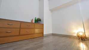 Una habitación con un armario de madera, una planta pequeña y una lámpara decorativa.