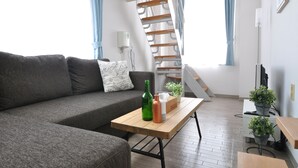 Una sala moderna con un sofá gris, una mesa de centro de madera y una escalera con barandilla de madera.