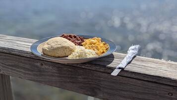 Un plato de comida sobre una barandilla de madera con una vista panorámica al fondo.