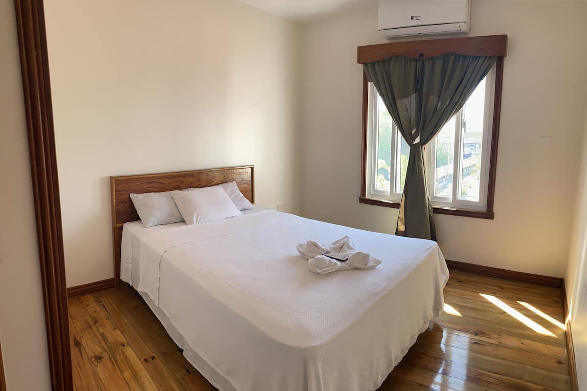 A neatly made bed with a wooden headboard, a white bedspread, and a towel arrangement.