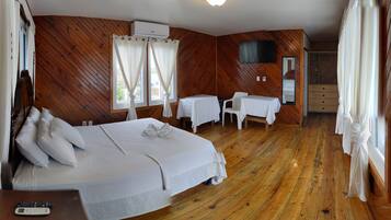 A room with a wooden floor, a bed, a desk, a chair, and a TV.