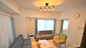 Ein Wohnzimmer mit Sofa, Sessel, Couchtisch und einer Deckenleuchte.