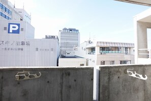 A parking area with a 'P' sign, concrete barriers, and a building with a modern design in the background. - IK Minami6Jo Residence 1003 (Sapporo)