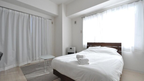 A modern hotel room with a large bed, a small table, and a window with curtains. - IK Minami6Jo Residence 301 (Sapporo)