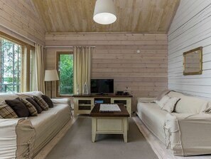 El interior de una cabaña con dos sofás, un televisor y una mesa.