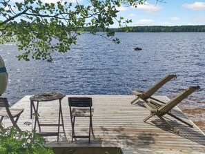 A wooden deck with lounge chairs and a table overlooking a lake. - Vacation home Kantri by Interhome (Ruokolahti)