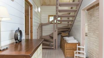 A wooden interior with a staircase, a wooden bench, and a small table with a clock.