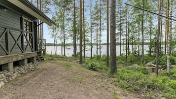 En stuga med en grusgång som leder till en brygga, omgiven av höga träd och en sjö eller ett annat vattendrag.