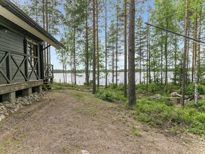 A cabin with a gravel path leading to a dock, surrounded by tall trees and a body of water. - Vacation home Kantri by Interhome (Ruokolahti)