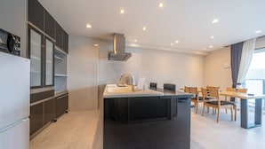 A modern kitchen with a central island, built-in appliances, and a dining area with a table and chairs. - Residence Hotel Takayama Station (Takayama)