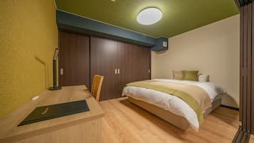 A bedroom with a bed, a desk, and a chair.