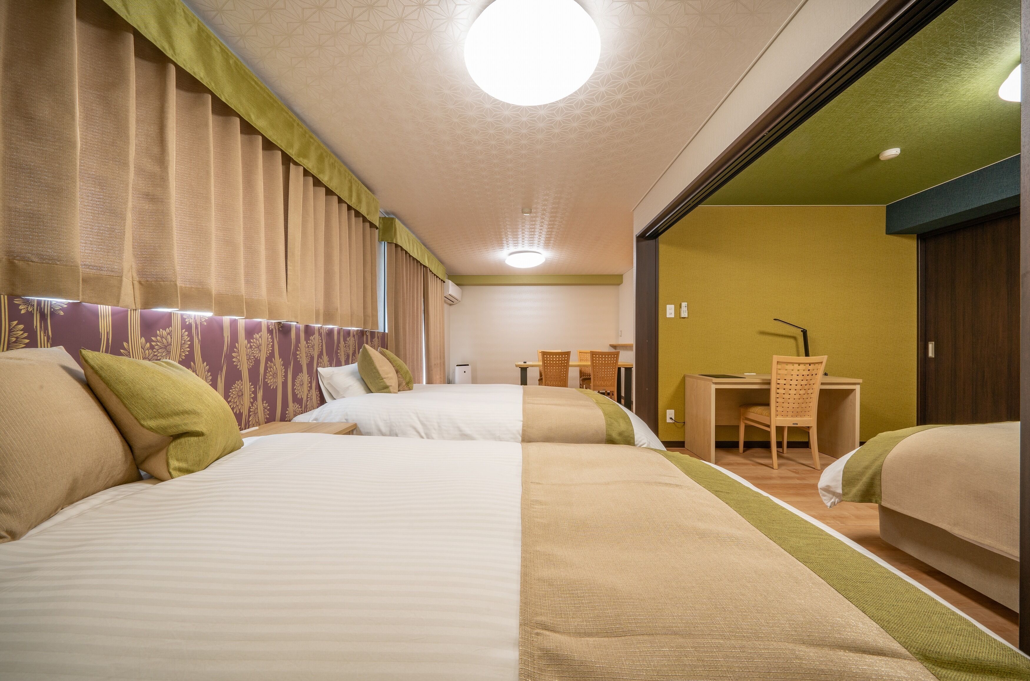 A hotel room with two beds, a desk, and a chair.
