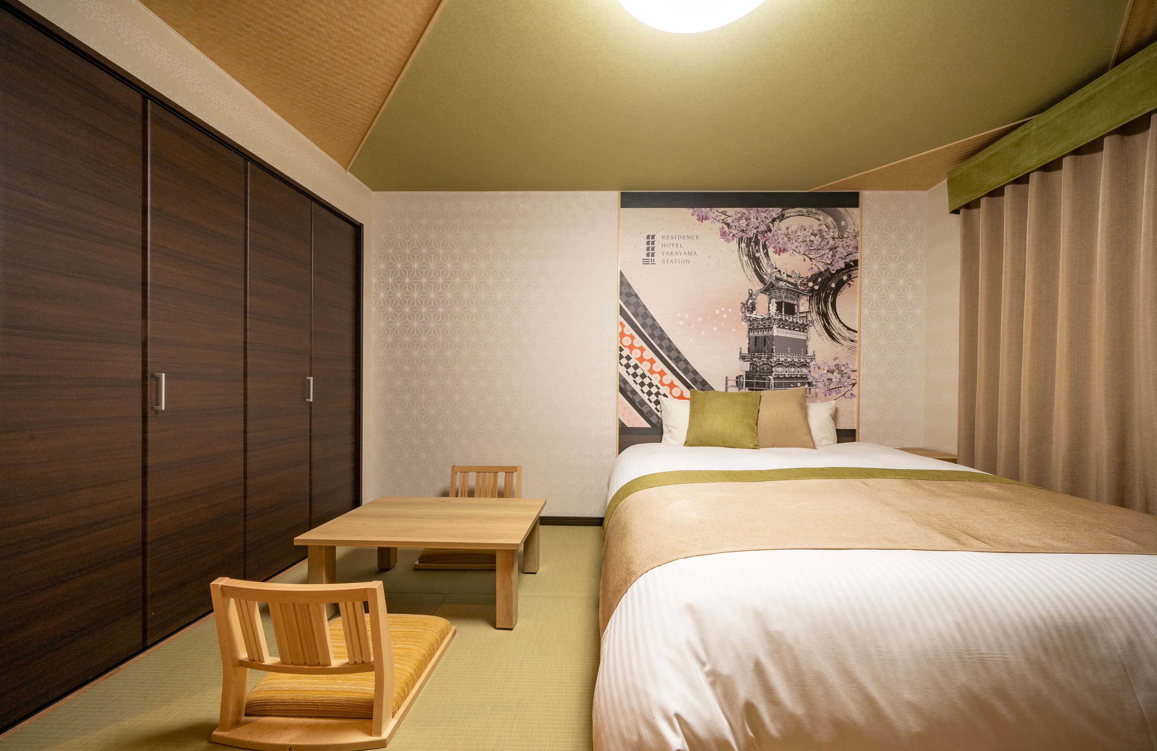 A hotel room with a bed, a wooden chair, a small table, and a wardrobe.