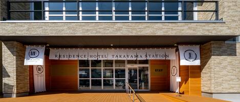 L’extérieur de l’hôtel Residence Hotel Takayama Station se distingue par son design moderne, avec une terrasse en bois et une signalétique claire.