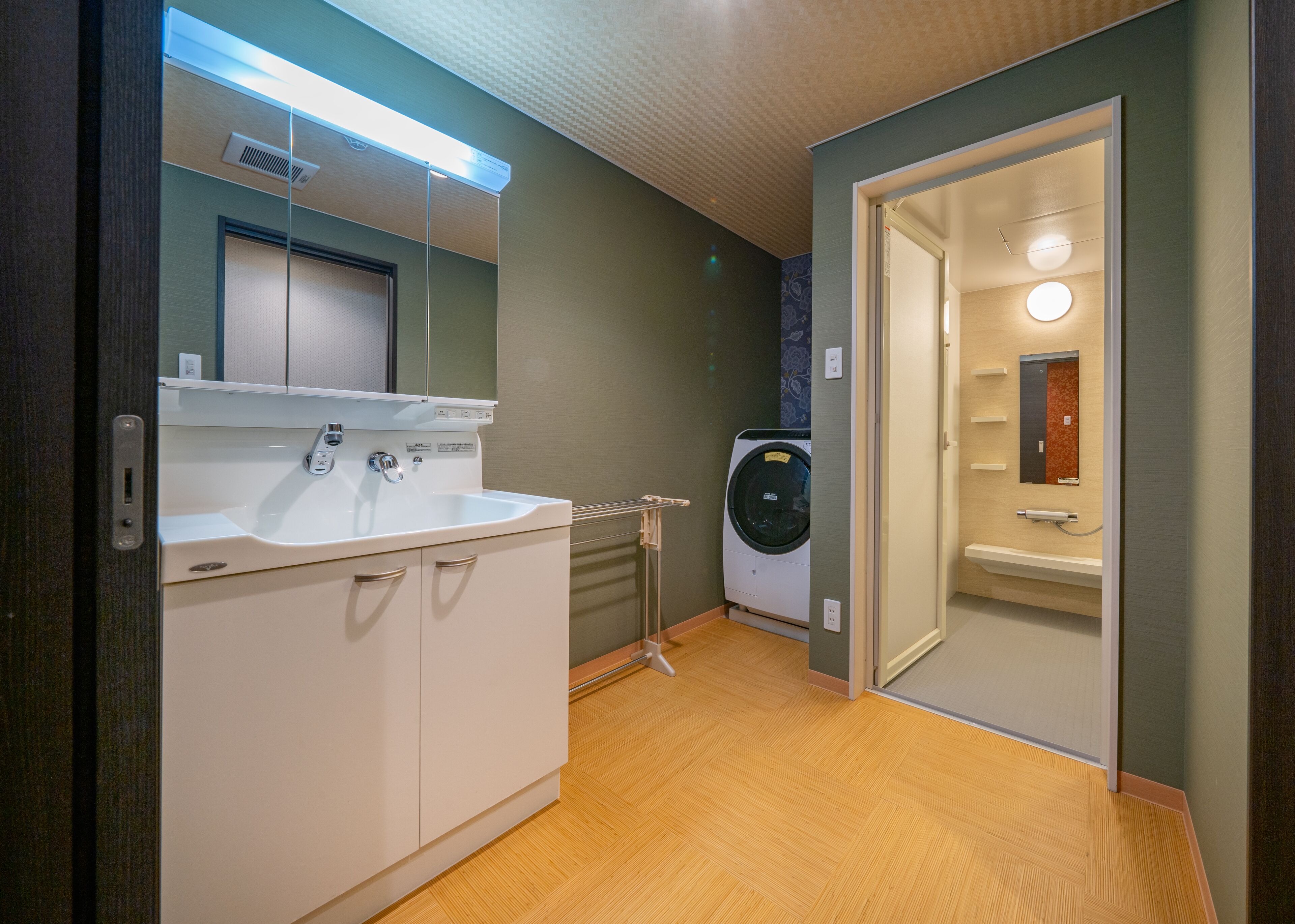 Een moderne badkamer met een wastafel, spiegel en een ingebouwde wasmachine.