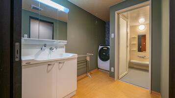 A modern bathroom with a sink, mirror, and a built-in washing machine.