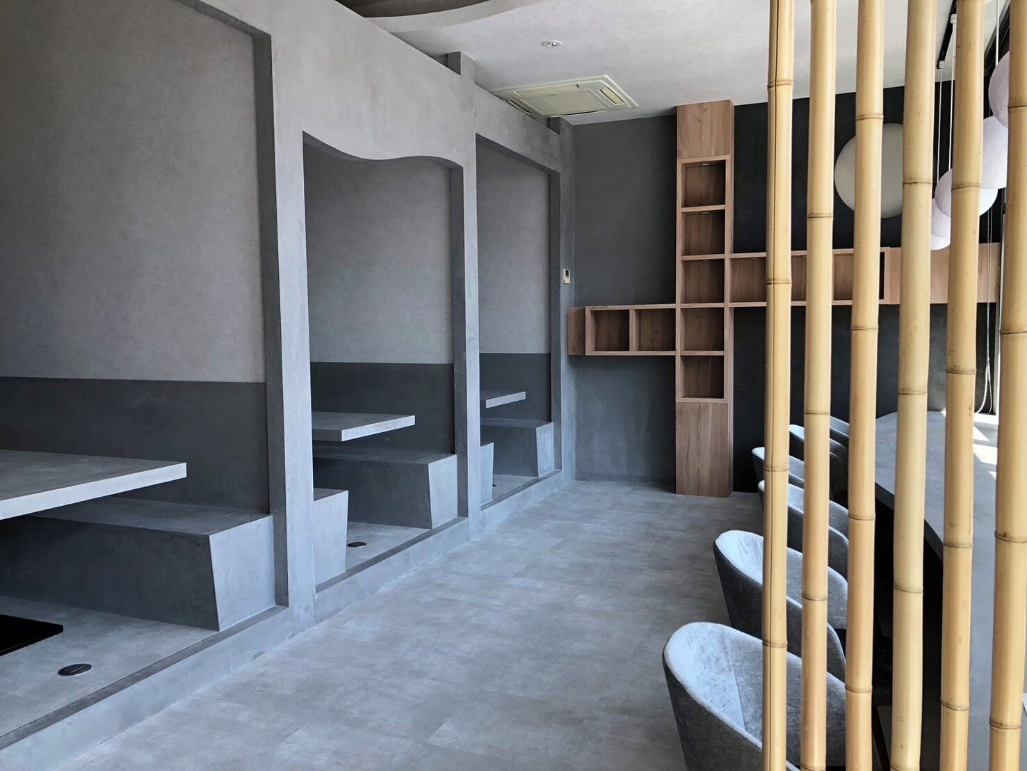En modern inredning med bänkar och hyllor i betong, inslag av bambu och en stilren, minimalistisk design.