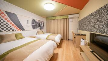 Habitación de hotel con dos camas, un escritorio, un televisor y una pared con diseño a cuadros y motivos florales.