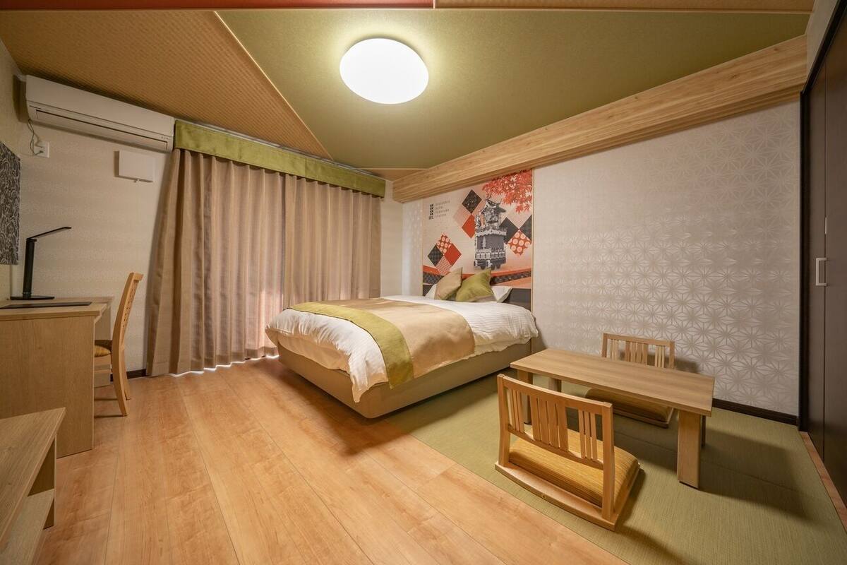 A room with a bed, a desk, a chair, and a small table.