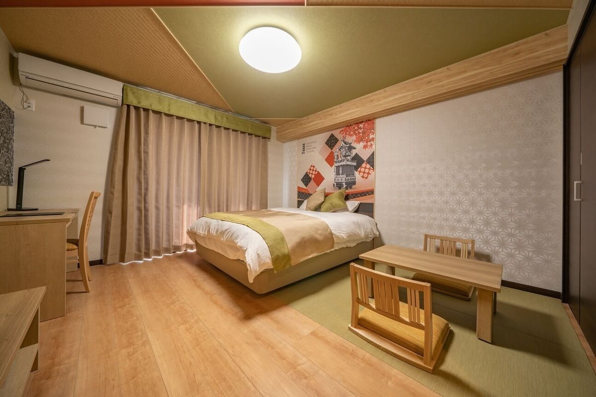 A room with a bed, a desk, a chair, and a small table.