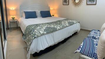 Een keurig opgemaakt slaapkamer met een bed, twee bedlampjes en een decoratief wandobject.