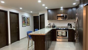 A modern kitchen with dark wood cabinets, stainless steel appliances, and a granite countertop.