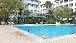 A swimming pool surrounded by a building with multiple balconies and a covered pavilion. - Large Studio Baan Suan Lalana (Pattaya)