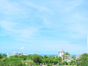 A coastal cityscape with buildings, greenery, and a clear sky.
