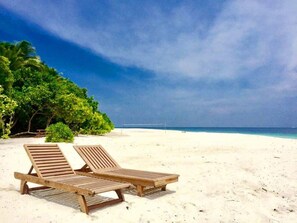 In Strandnähe, weißer Sandstrand, Liegestühle, Sonnenschirme