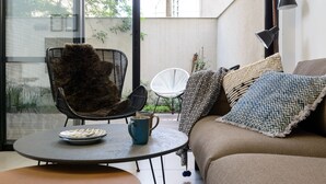 A cozy seating area with a round table, a sofa, and two chairs. - Garden 1 Bedroom Apartment (Tel Aviv)