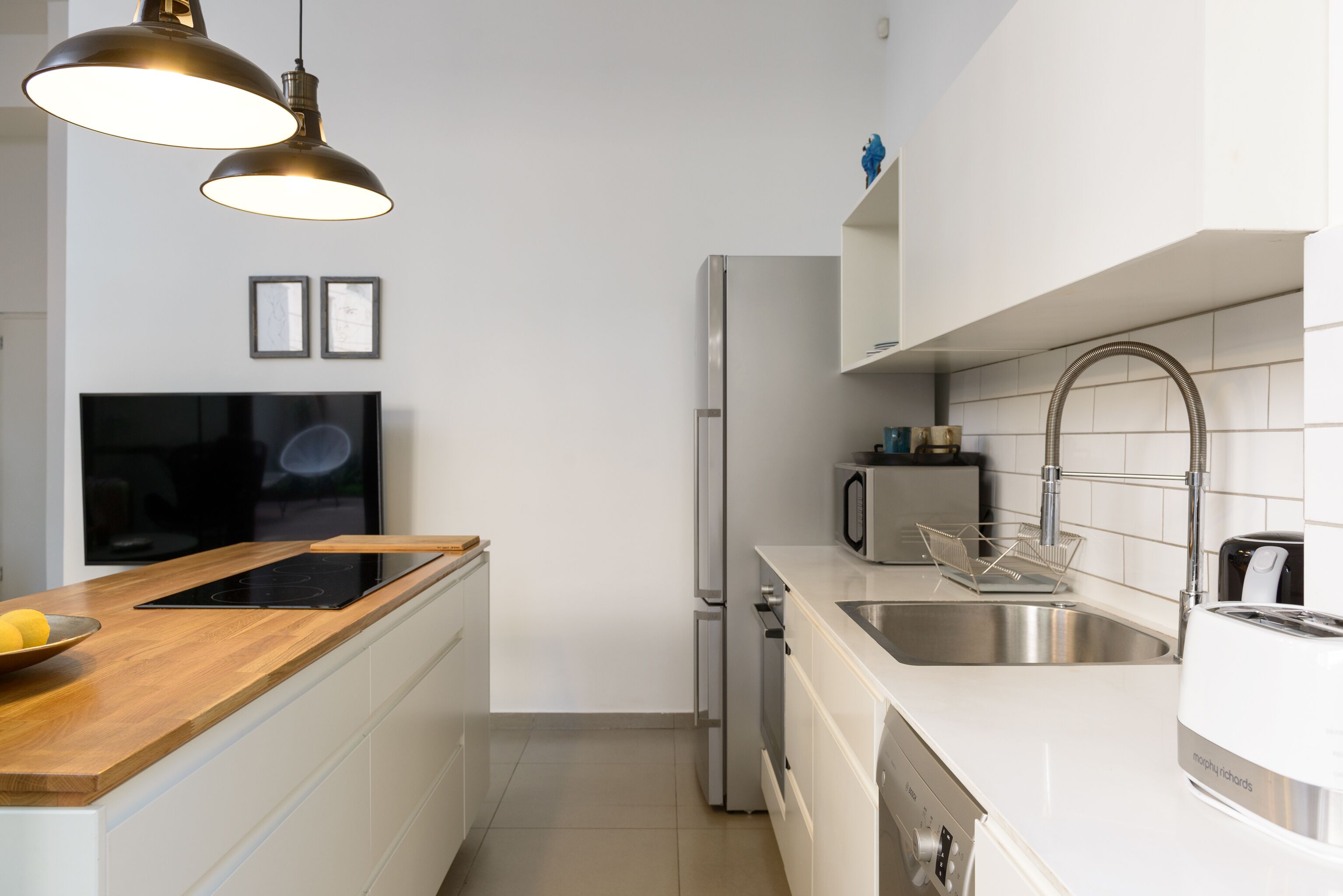 Uma cozinha moderna com bancada de madeira, eletrodomésticos de aço inoxidável e iluminação pendente.