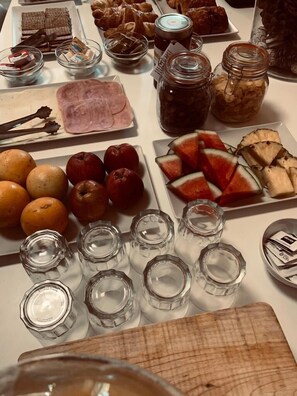 Une table où sont présentés divers aliments, notamment des fruits, des pâtisseries et des condiments.