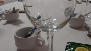 Een eettafel met een wijnglas, een koffiekop en een pakje citroenthee.