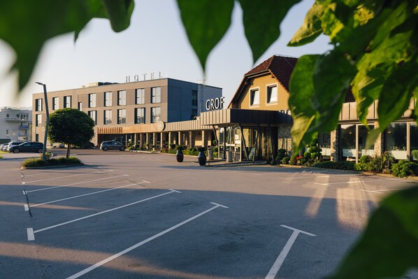 A hotel with a modern design, featuring a mix of glass and stone facades, and a parking lot in the foreground. - Hotel Grof (Vransko)